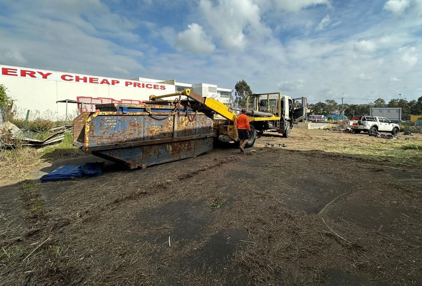 Skip bin on a driveway filled with timber and household junk