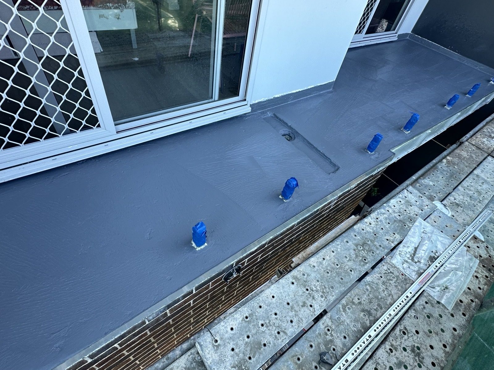 Fresh grey waterproofing membrane on a balcony ledge